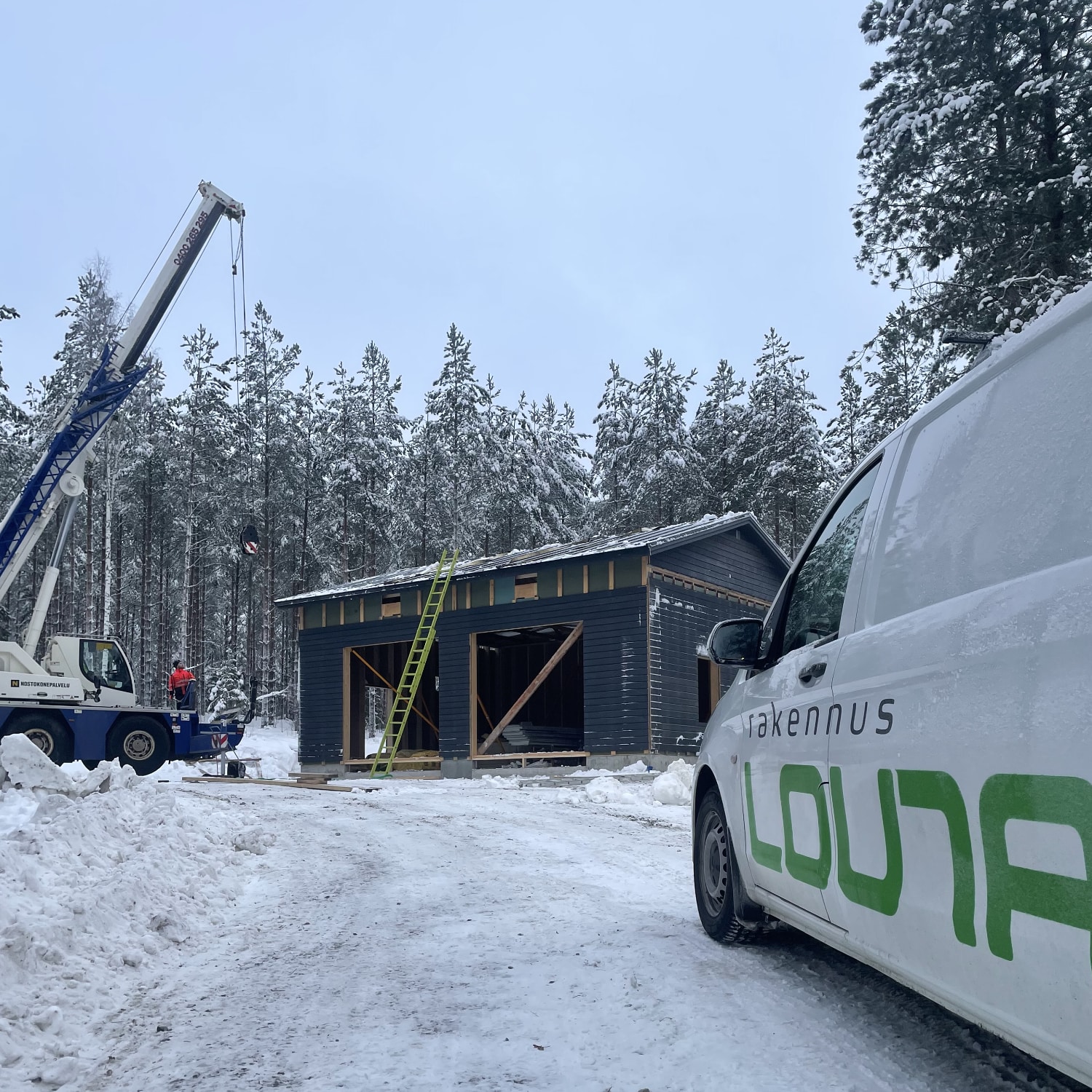 Rakennus Lounan pakettiauto etualalla ja taka-alalla autokatoksen rakennustyot kaynnissa.